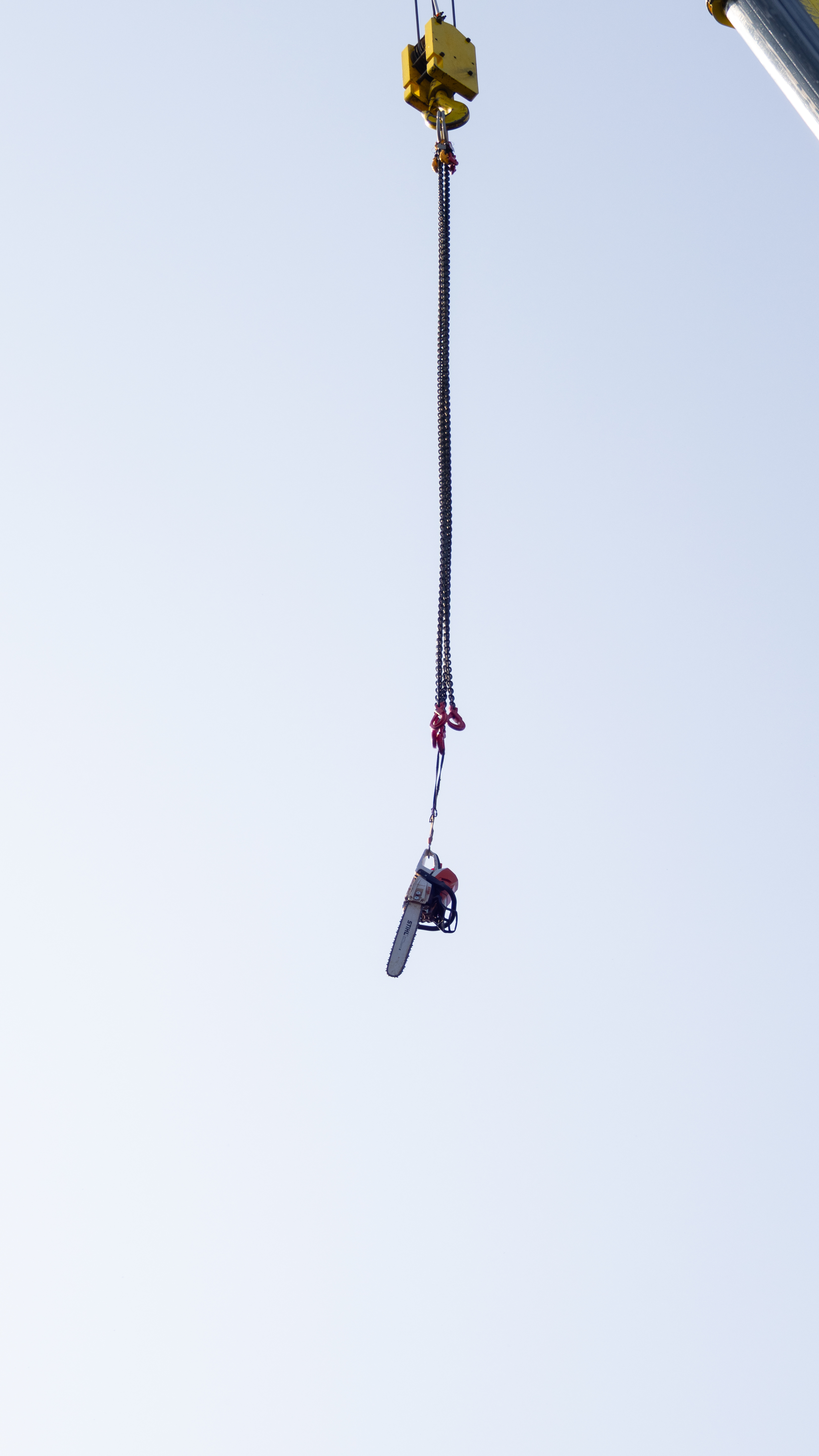 Tronçonneuse suspendue à une grue sur un chantier de sous-traitance